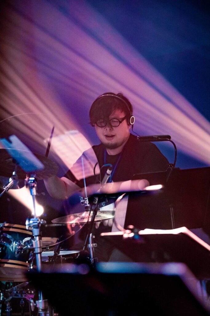 Po Chan, a drum instructor, is playing the drums during a live stage performance as a professional musician.