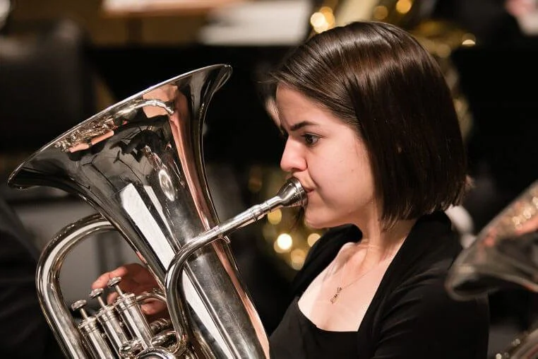 An euphonium player is performing on stage during a concert.