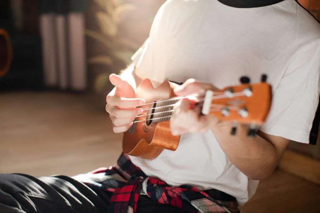 A teacher is showing how to play ukulele in a lesson.